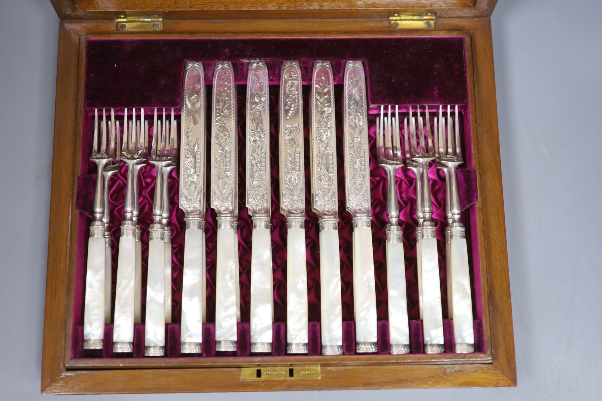 A Victorian walnut cased set of twelve pairs of mother of pearl handled dessert eaters, Frederick Elkington, Birmingham, 1888,